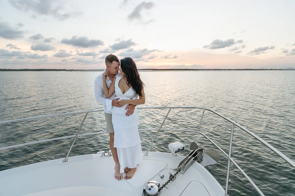 Romarie and Jake standing at the bow of the boat beneath a sky of scattered cloud