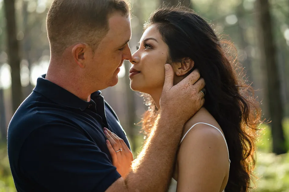 Jake’s hand on Romarie’s cheek as they lean in close, the forest bright behind them