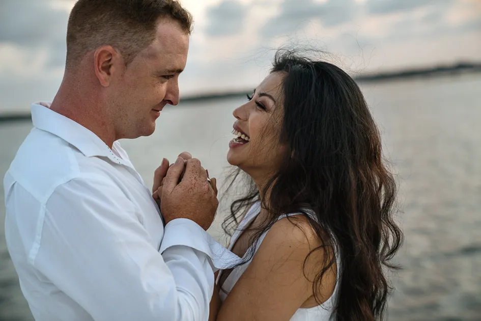 Romarie and Jake laughing together, hands clasped, out on the water