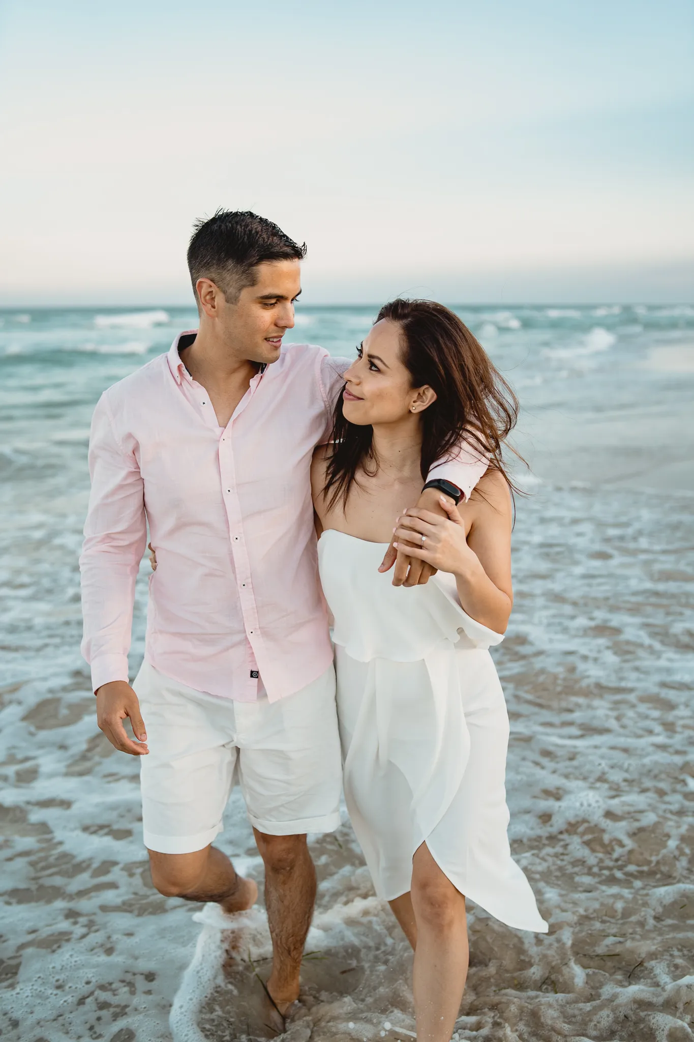 Rafaela and Mark walking arm in arm through the shallows
