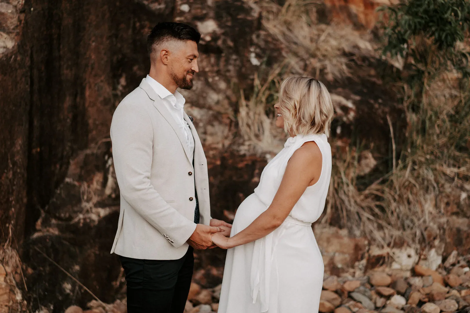 Shannon and Jacksen holding hands against a rock wall