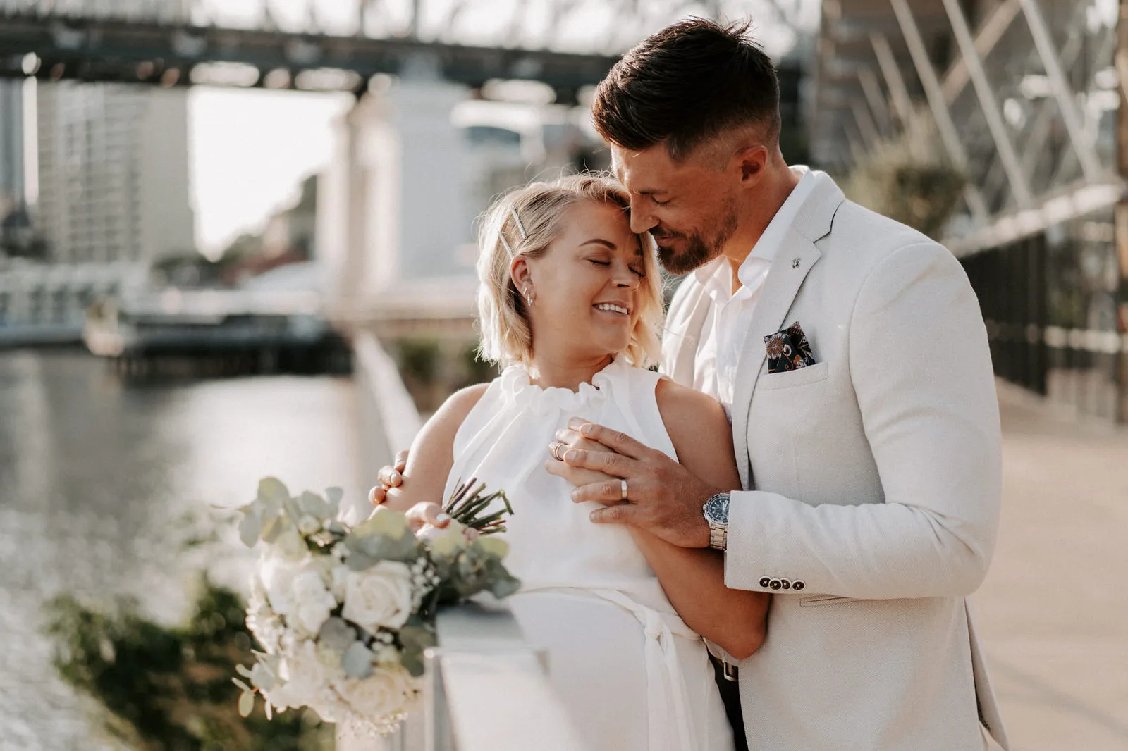 Shannon and Jacksen by the river, her bouquet in hand, the Story Bridge behind them