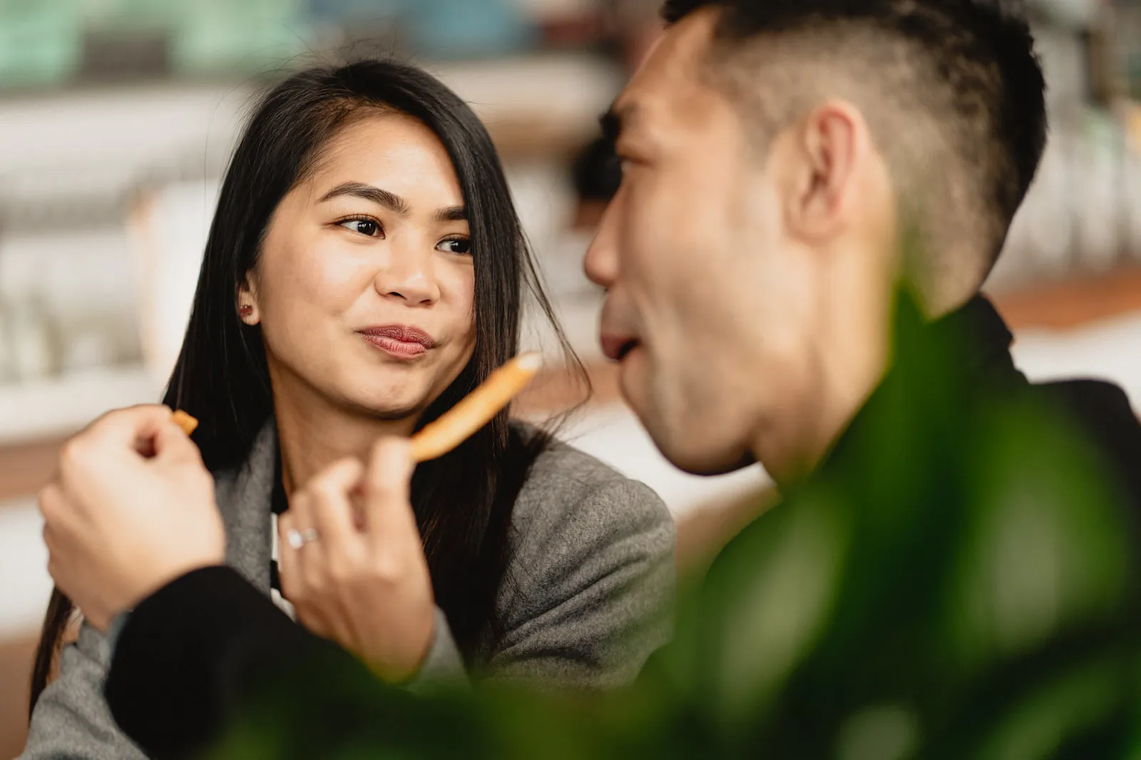 Zaneta smiling at Vryan as she shares a chip with him in a café