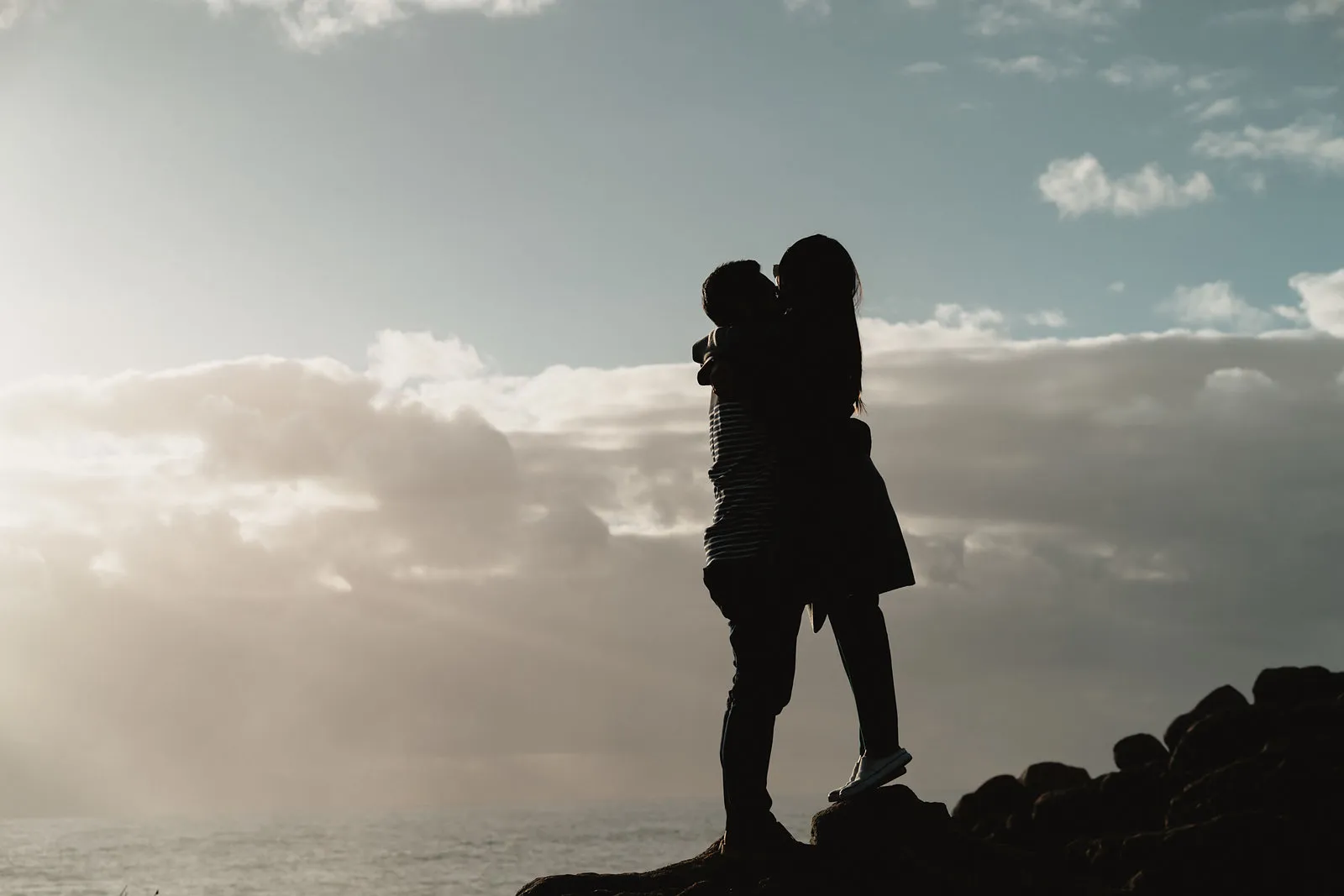 Zaneta and Vryan embracing in silhouette against the sky