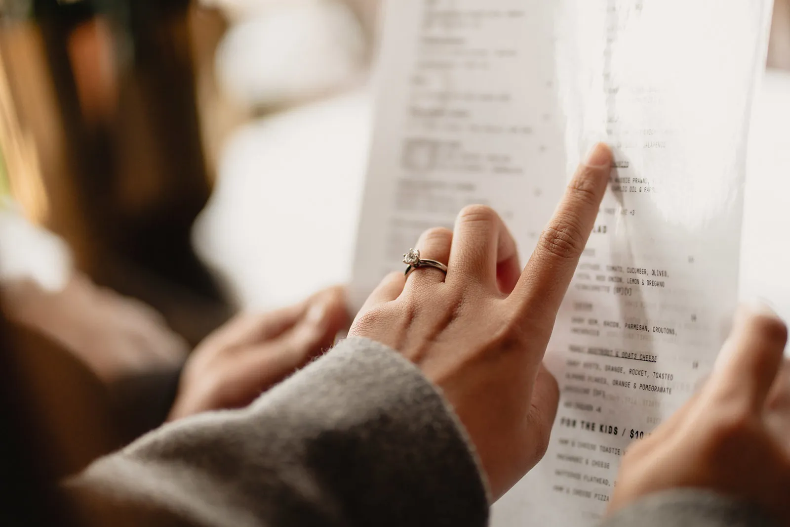 Zaneta pointing at a menu, her engagement ring in view