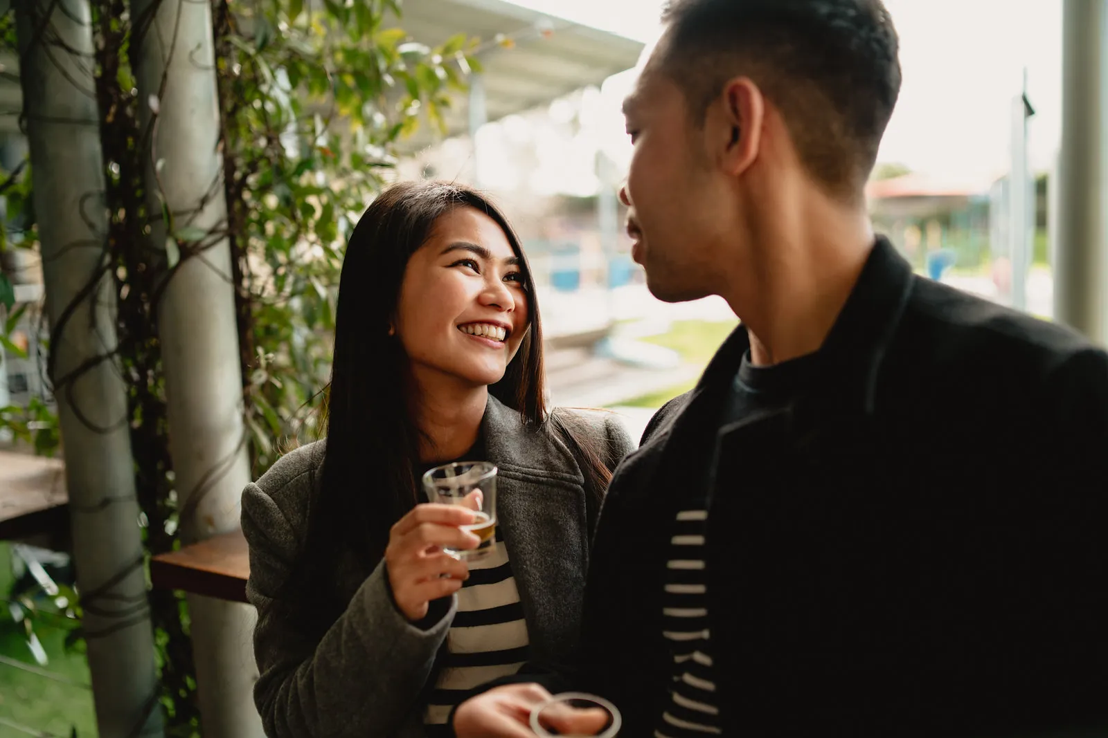 Zaneta laughing with a drink in hand beside Vryan at a café