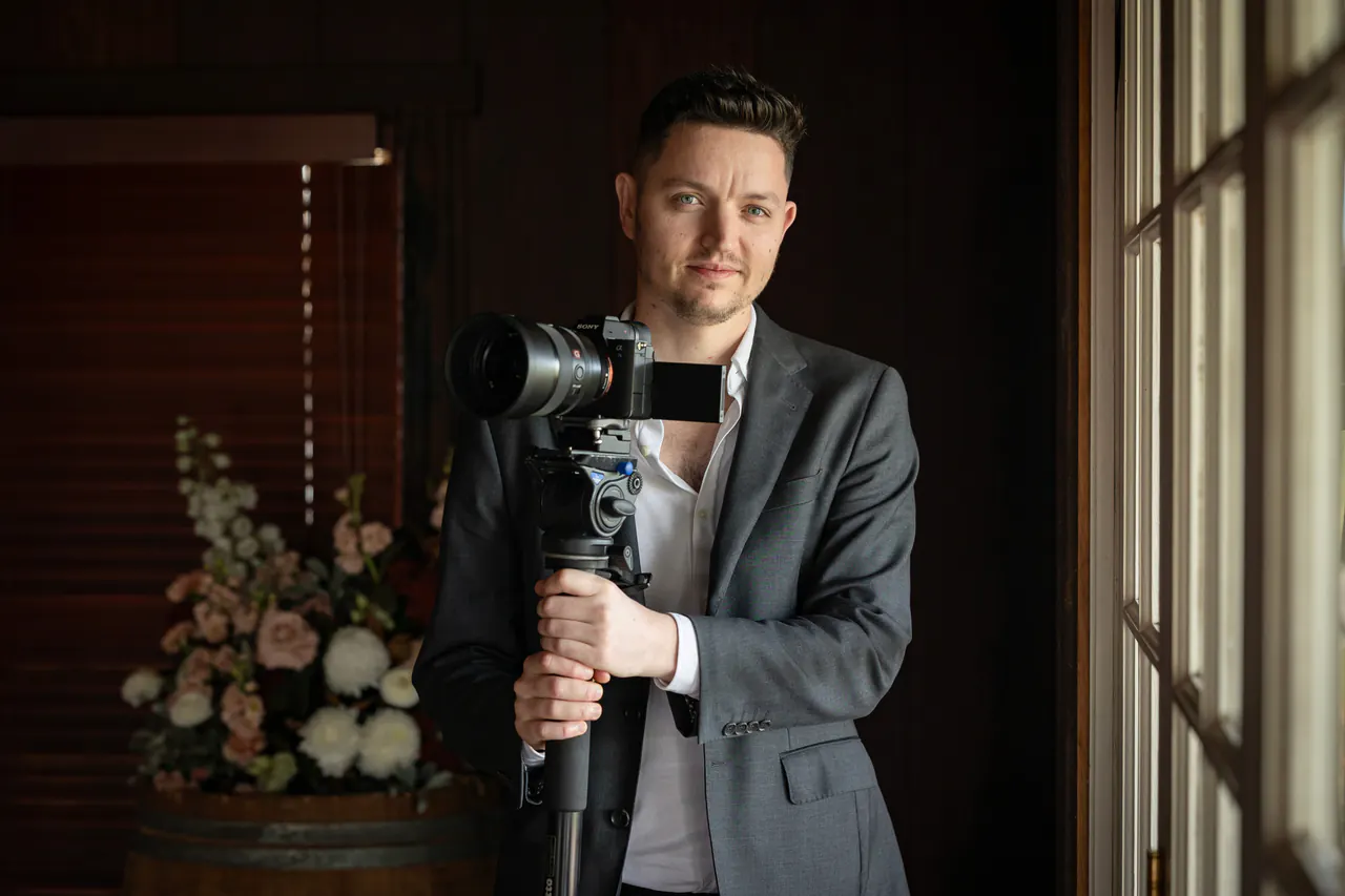Ben Fairhurst holding his camera beside a window