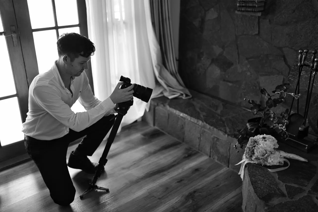 Ben kneeling in window light, filming the wedding details