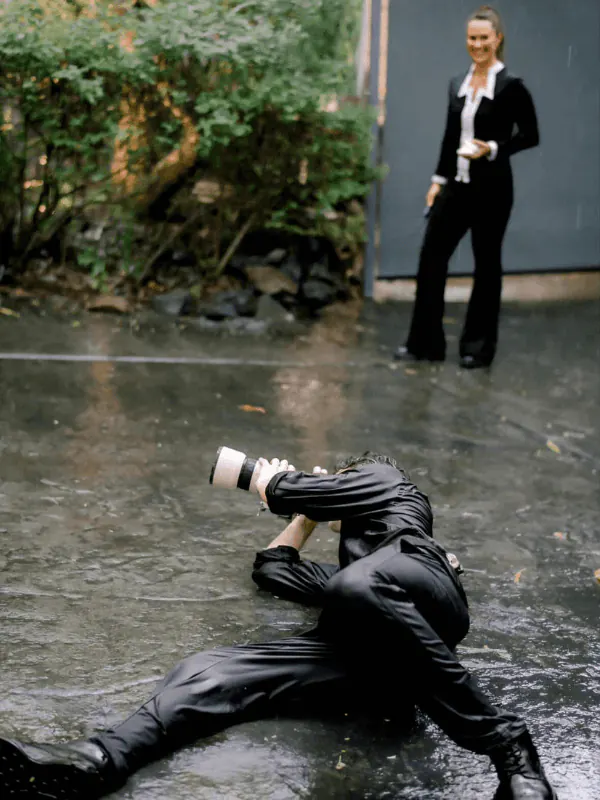 Ben lying on rain-soaked paving to film the bride from below