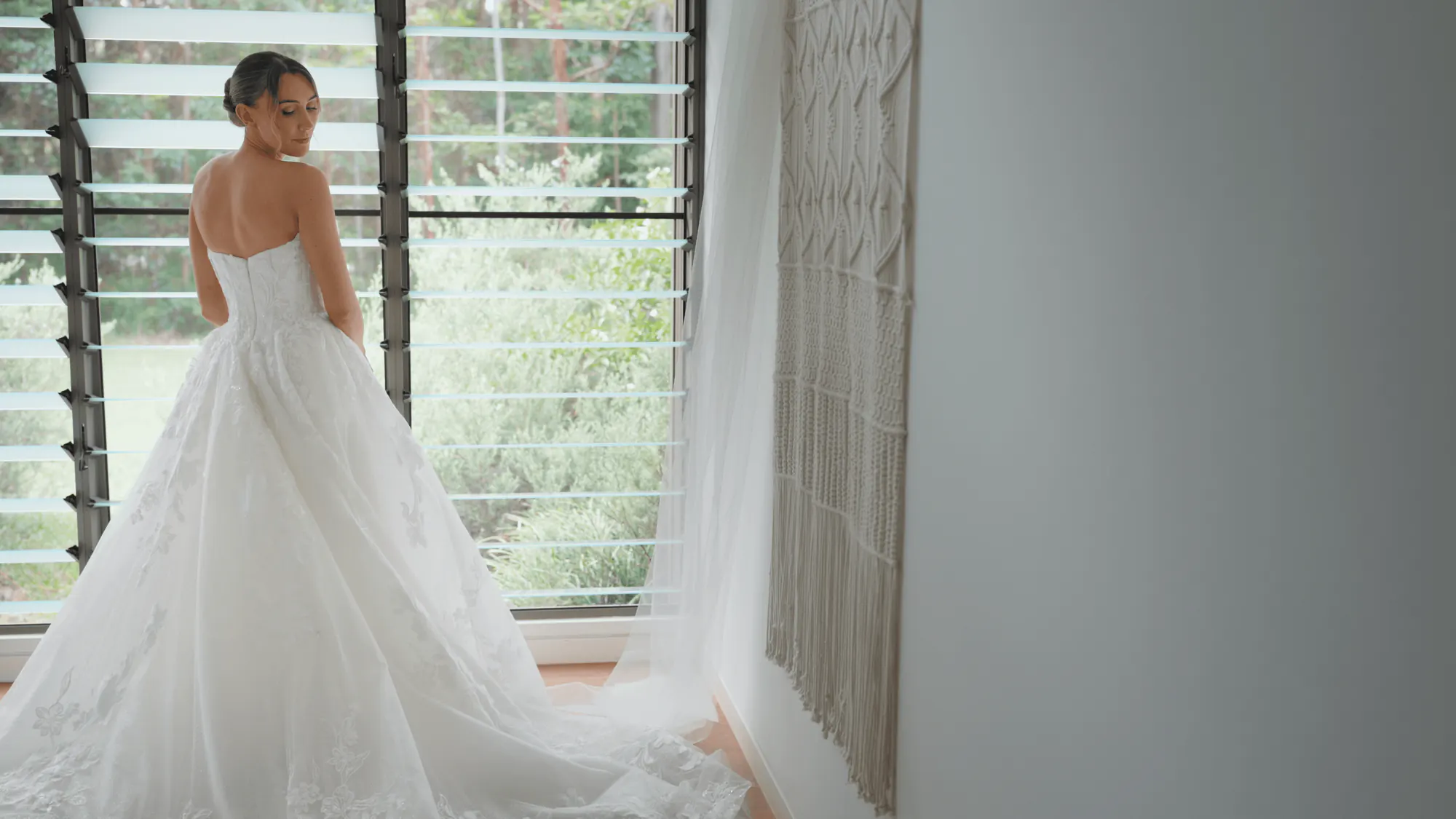 Shannon in her wedding gown by the louvred window